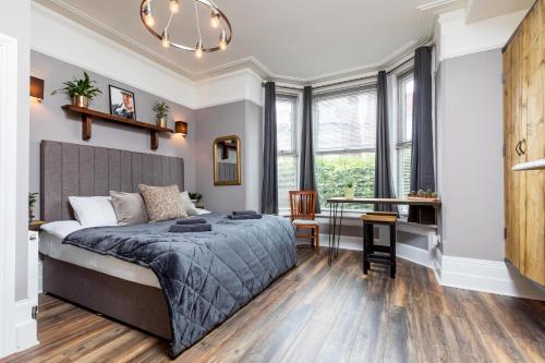 a bedroom with a bed and a desk and windows at Accudo House Boutique Holiday Suites in Portsmouth