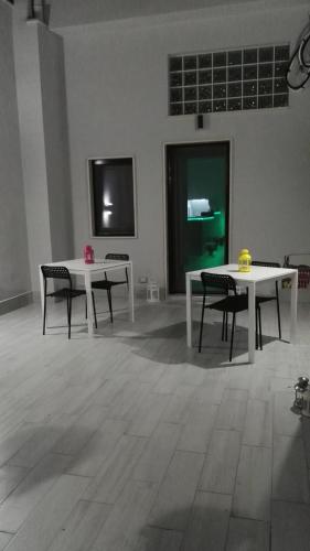 two white tables and chairs in a room with a wall at Marselo B&B in Bari