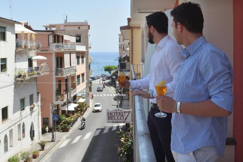 two men standing on a balcony with glasses of wine at Hotel7Bello in Minori