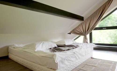a white bed in a room with a window at Pension Pîrîu' Morii in Gura Humorului
