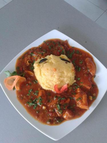 a white plate of food with a bowl of stew at Pension Pîrîu' Morii in Gura Humorului