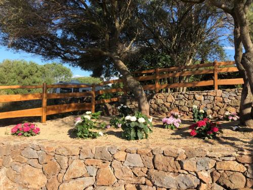 a stone wall with flowers in front of a fence at Country House S'Ozzastru in Dorgali
