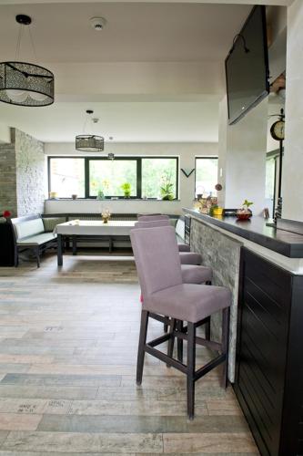 a kitchen with a bar with a chair and a living room at Pension Pîrîu' Morii in Gura Humorului