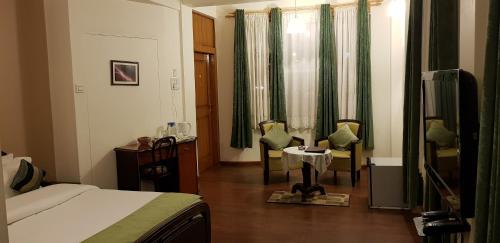 a hotel room with a bed and a table and chairs at Woodland Hill Stay in Shillong
