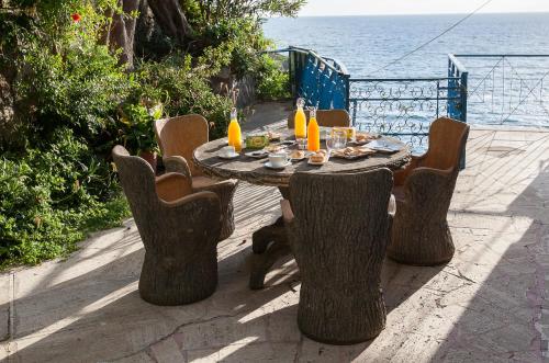 a wooden table with chairs and the ocean in the background at Oasi Relais in Vico Equense
