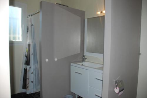 a white bathroom with a sink and a mirror at La Pause du Sentier in Sendets