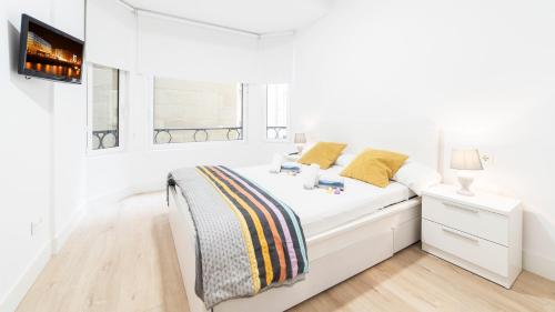 een witte slaapkamer met een bed en een televisie bij Central Luxury- SSHousing in San Sebastian