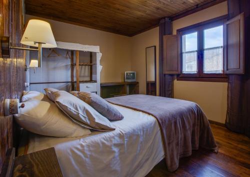 a bedroom with a bed with pillows and a window at Aldea Rural A Cortiña in Pepín