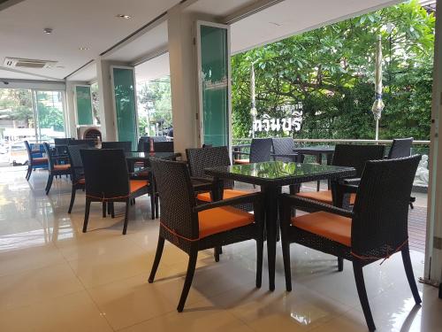a dining room with tables and chairs and windows at Kavin Buri Green Hotel in Udon Thani