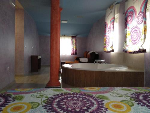baño con bañera y cama con alfombra en Hostal Orly, en Camponaraya