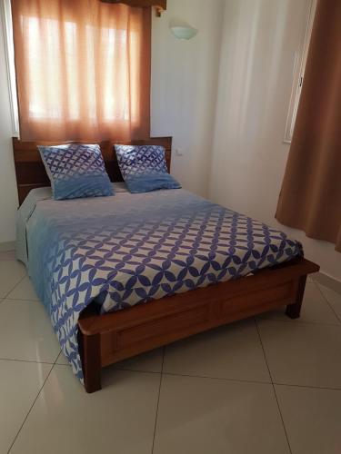 a bedroom with a bed with blue comforter and pillows at Villa Violette in Ambatoloaka