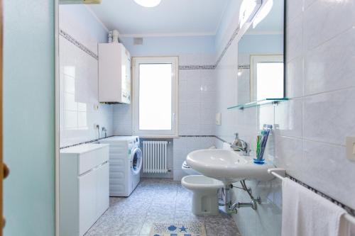 a white bathroom with a sink and a washing machine at Residence Kimba in Rimini