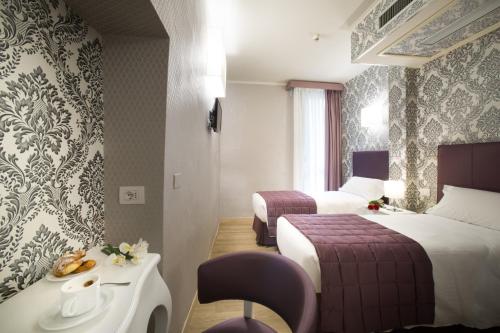 フィレンツェにあるホテル モントリオールのベッド2台、テーブル、シンクが備わるホテルルームです。