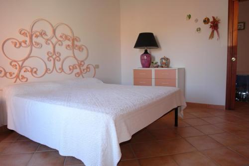 sypialnia z białym łóżkiem i komodą w obiekcie Appartamento La casa di Milena w mieście Barrabisa