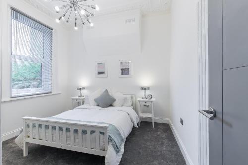 a white bedroom with a bed and a window at Maycourt Gem in London