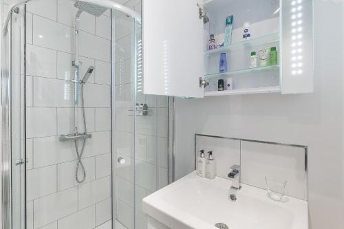 baño blanco con ducha y lavamanos en Maycourt Gem, en Londres