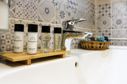 a bathroom sink with three products on a shelf at Napfény Apartman in Sopron