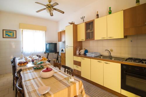 cocina con mesa de comedor y cocina con armarios amarillos en B&B Casa Paolo, en Fiumefreddo di Sicilia