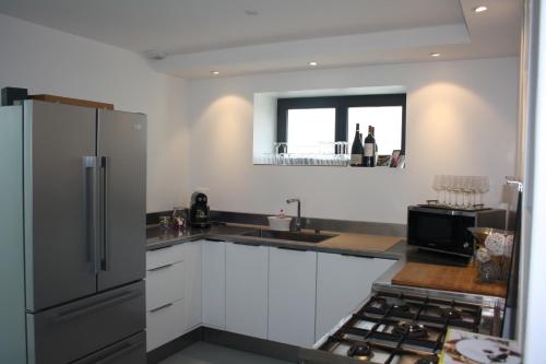 une cuisine avec des armoires blanches et un réfrigérateur en acier inoxydable dans l'établissement Maison de Poul Briel, à Saint-Guénolé