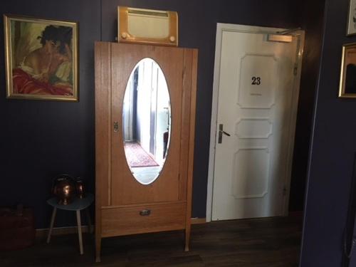 a mirror in a wooden cabinet next to a door at Pensionat Augustin in Gällivare