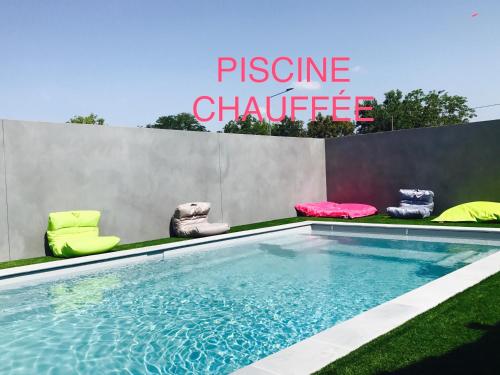 une piscine avec des chaises et un panneau indiquant le défi de la présence dans l'établissement Kyriad Direct Agen, à Castelculier