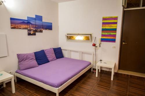 un letto viola in una stanza con due tavoli di Casa Lory a Napoli