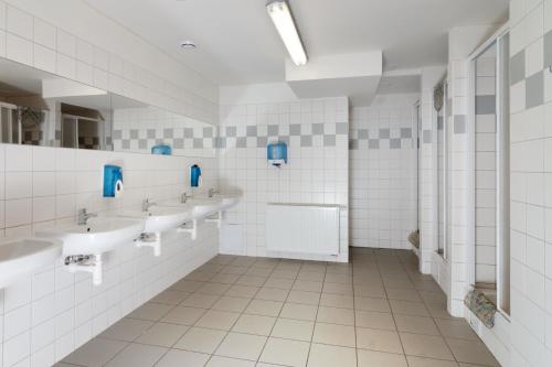 uma casa de banho com três lavatórios e uma fila de espelhos em Ubytovani Rico em Vrchlabí