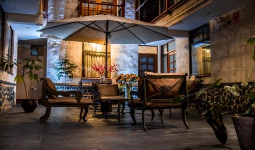 a patio with a table and chairs and an umbrella at El Portal De San Lázaro in Arequipa