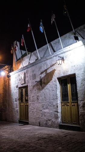 a building with flags on the side of it at night at El Portal De San Lázaro in Arequipa