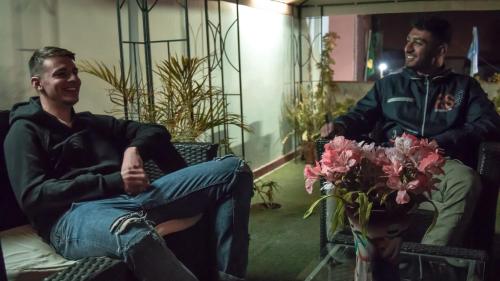 two men sitting in chairs in a room with flowers at El Portal De San Lázaro in Arequipa