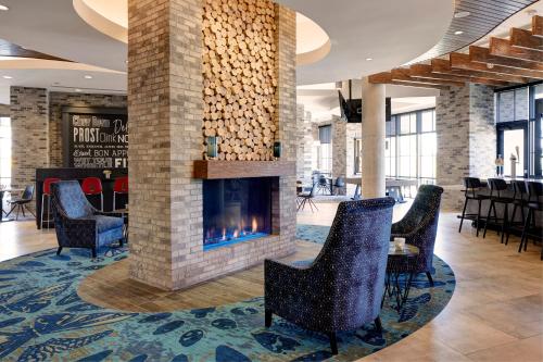 a fireplace in a lobby with chairs and tables at Archer Hotel Florham Park in Florham Park