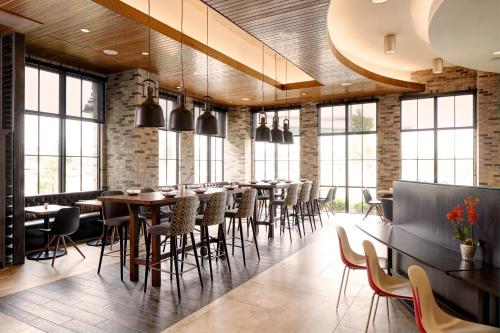 a restaurant with tables and chairs and windows at Archer Hotel Florham Park in Florham Park