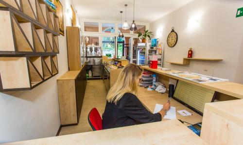 a woman sitting at a counter in a store at Student's Hostel Estense in Ferrara