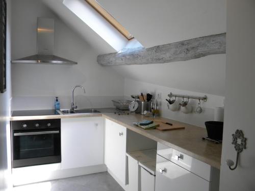 une cuisine avec des armoires blanches et un évier dans l'établissement Le jardin des chanceliers, à Beaune