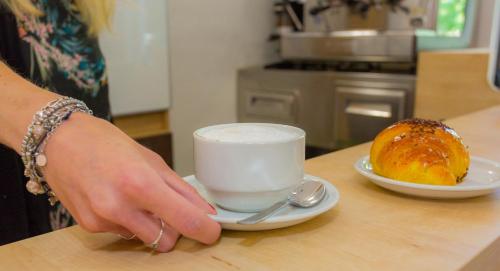 a person holding a cup of coffee and a pastry on a table at Student's Hostel Estense in Ferrara