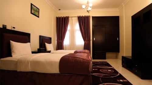 a bedroom with a large bed and a window at Remas Hotel Suites - Al Khoudh, Seeb, Muscat in Seeb