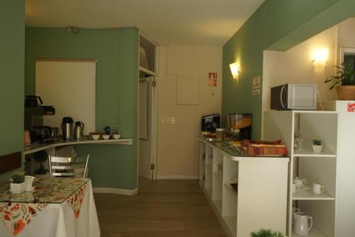 a kitchen with green walls and a table in a room at De la Plaza Hotel in Maldonado
