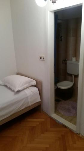 a bedroom with a bed and a bathroom with a toilet at Apartment House Aria in Baška Voda