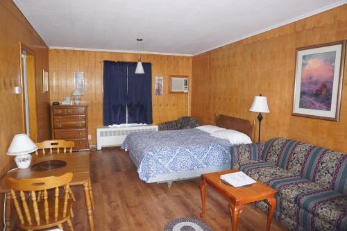 a bedroom with a bed and a couch and a table at Northern Peaks Motor Inn in Gorham