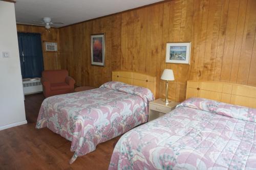 a hotel room with two beds and a chair at Northern Peaks Motor Inn in Gorham