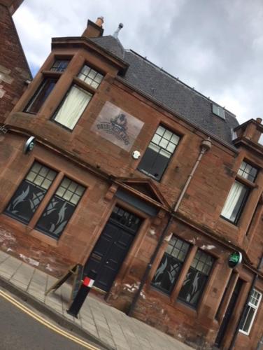 a brick building with a black door on a street at Dryburgh Arms Pub with Rooms in Melrose