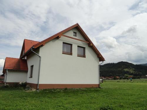 a white house with a red roof in a field at Apartmany Tania in Závažná Poruba