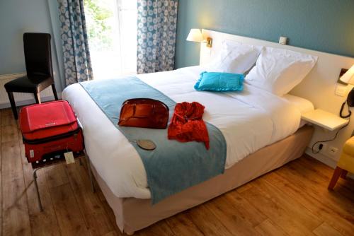 a hotel room with a bed with luggage on it at LOGIS Hotel Majestic Chatelaillon Plage - La Rochelle in Châtelaillon-Plage