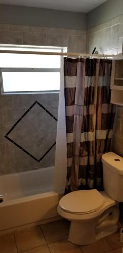 a bathroom with a toilet and a shower curtain at INN LEATHER GUEST HOUSE-GAY MALE ONLY in Fort Lauderdale
