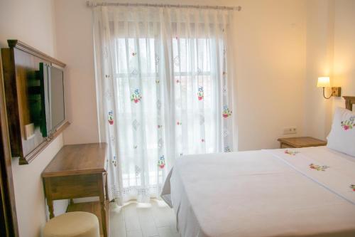 a bedroom with a white bed and a window at Monza House Otel in Siğacık