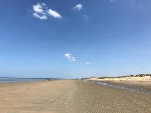a beach with people walking on the sand and the ocean at Koksijde App Zeelaan B3 in Koksijde