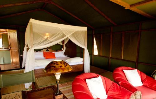 - une chambre avec un lit et deux chaises dans l'établissement Sable Mountain Lodge, A Tent with a View Safaris, à Kisaki