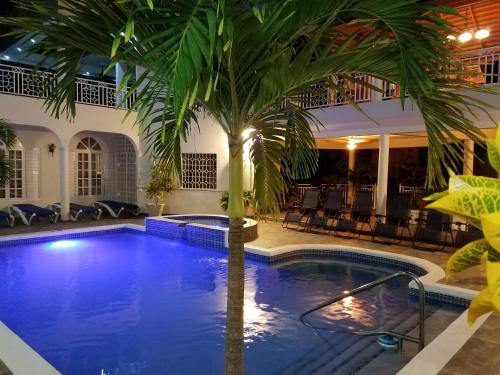 a pool with a palm tree next to a hotel at Mais Oui Villa in Discovery Bay