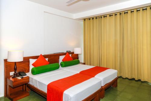 a bedroom with a large bed with red and green pillows at Fresco Water Villa in Sigiriya