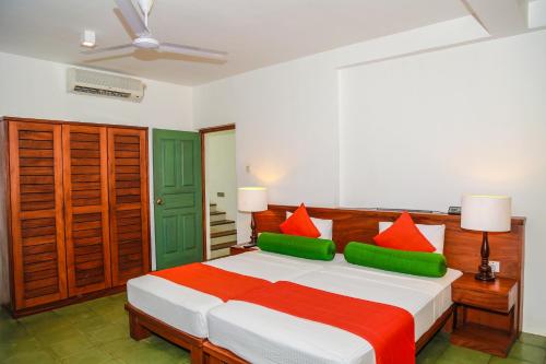 a bedroom with a bed with red and green pillows at Fresco Water Villa in Sigiriya